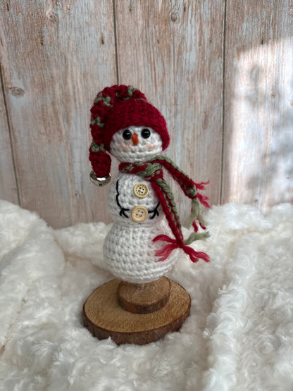 Handmade Crochet Snowman with Hat and Scarf – Winter Table Decor, Crochet Snowman on Wooden Base – Cozy Rustic Christmas Decoration, Mini Crochet Snowman – Cute Handmade Holiday Figurine, Crochet Snowman with Button Details – Perfect Winter Gift